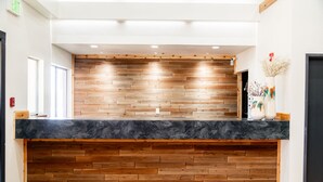 A reception desk with a wooden panel backdrop and a black marble counter. - OK Welcome Home Hotel (Alva)