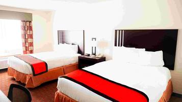 A hotel room with two beds, a nightstand, a lamp, and a window with curtains.
