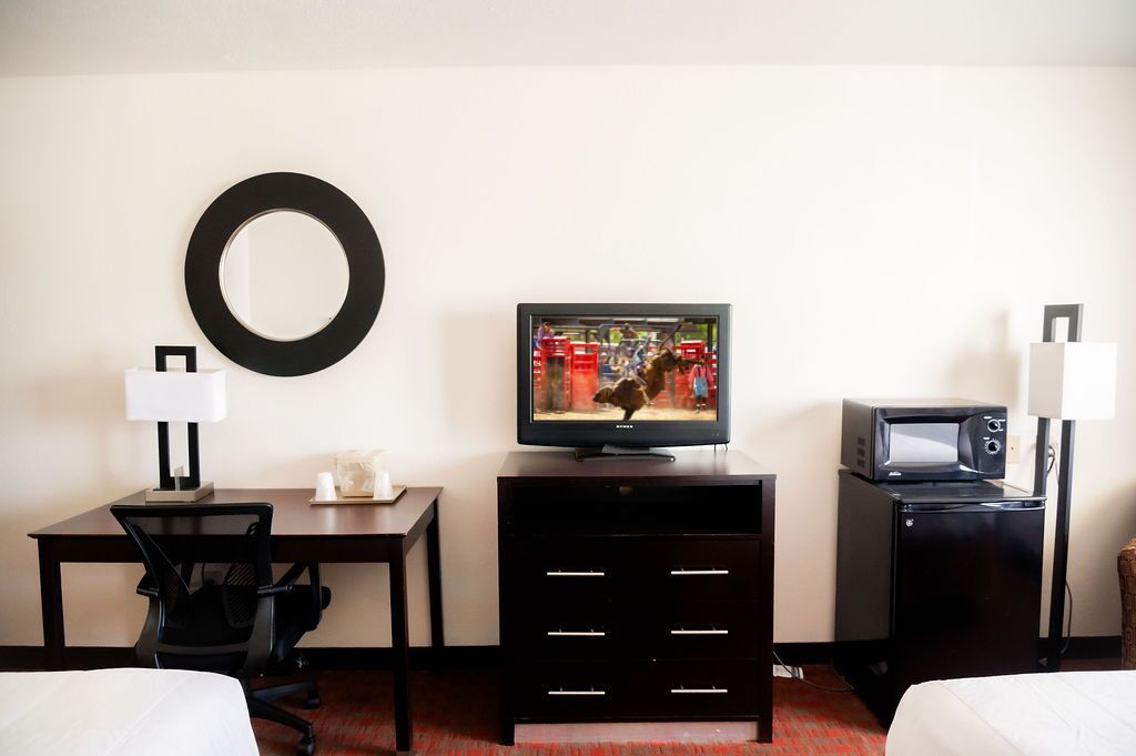 Habitación de hotel con escritorio, silla, televisor y microondas.
