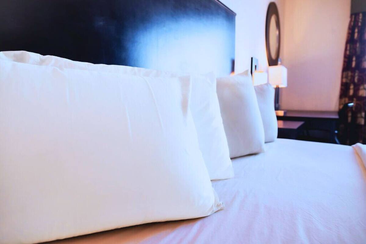 Een hotelkamer met een net opgemaakt bed, een grote flatscreen-tv en een wandlamp.