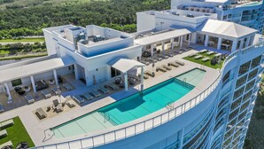 Un hôtel de grande hauteur doté d’une piscine sur le toit, d’un espace extérieur aménagé et offrant une vue sur la verdure environnante.