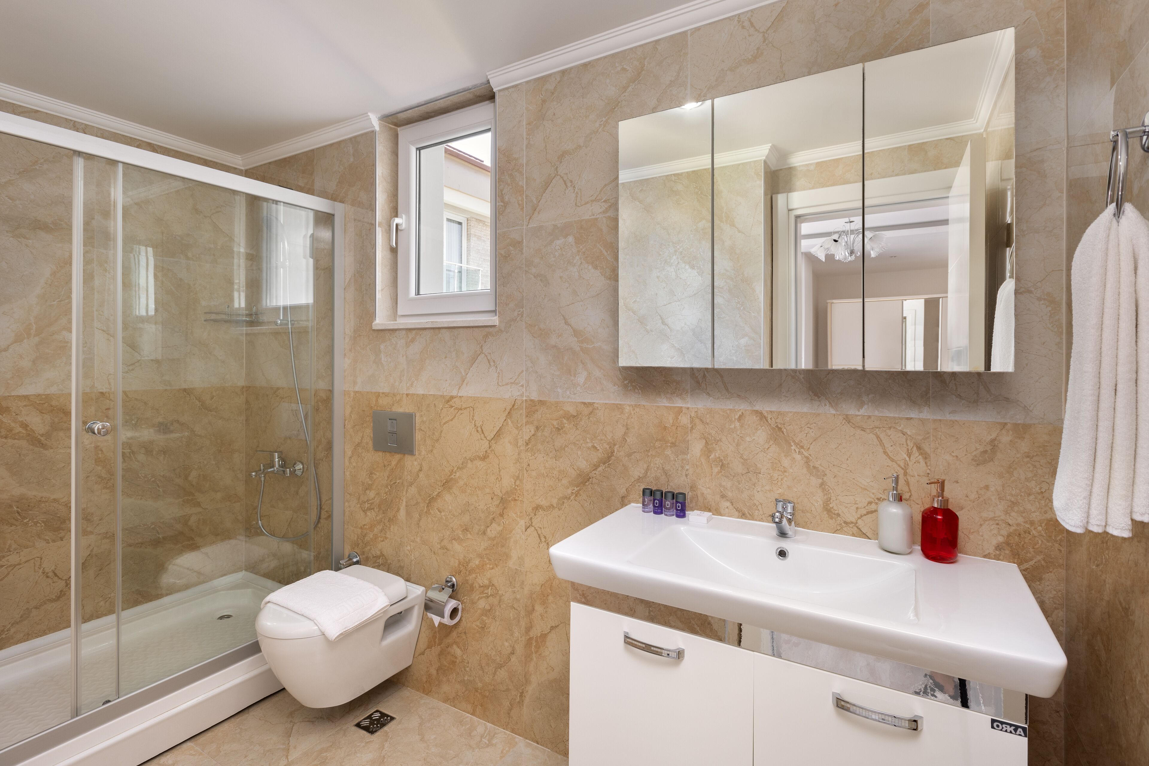 Een badkamer met een douche met glazen wand, een wit wastafelmeubel en een grote spiegel.