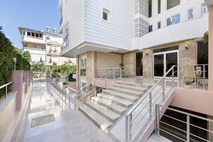 A modern building with a central staircase, a covered outdoor area, and a second-floor balcony.