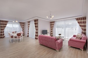 A spacious living room with a dining area, pink sofas, and a chandelier.