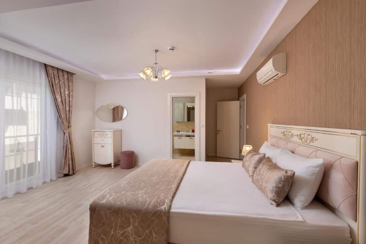 A hotel room with a large bed, a bedside table, a mirror, and a wardrobe.