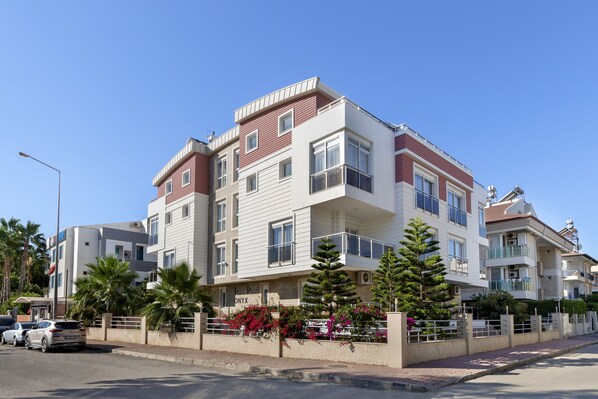 A multi-story residential building with balconies, a gated entrance, and a clear sky. - Onix Apart Hotel (Konyaalti)