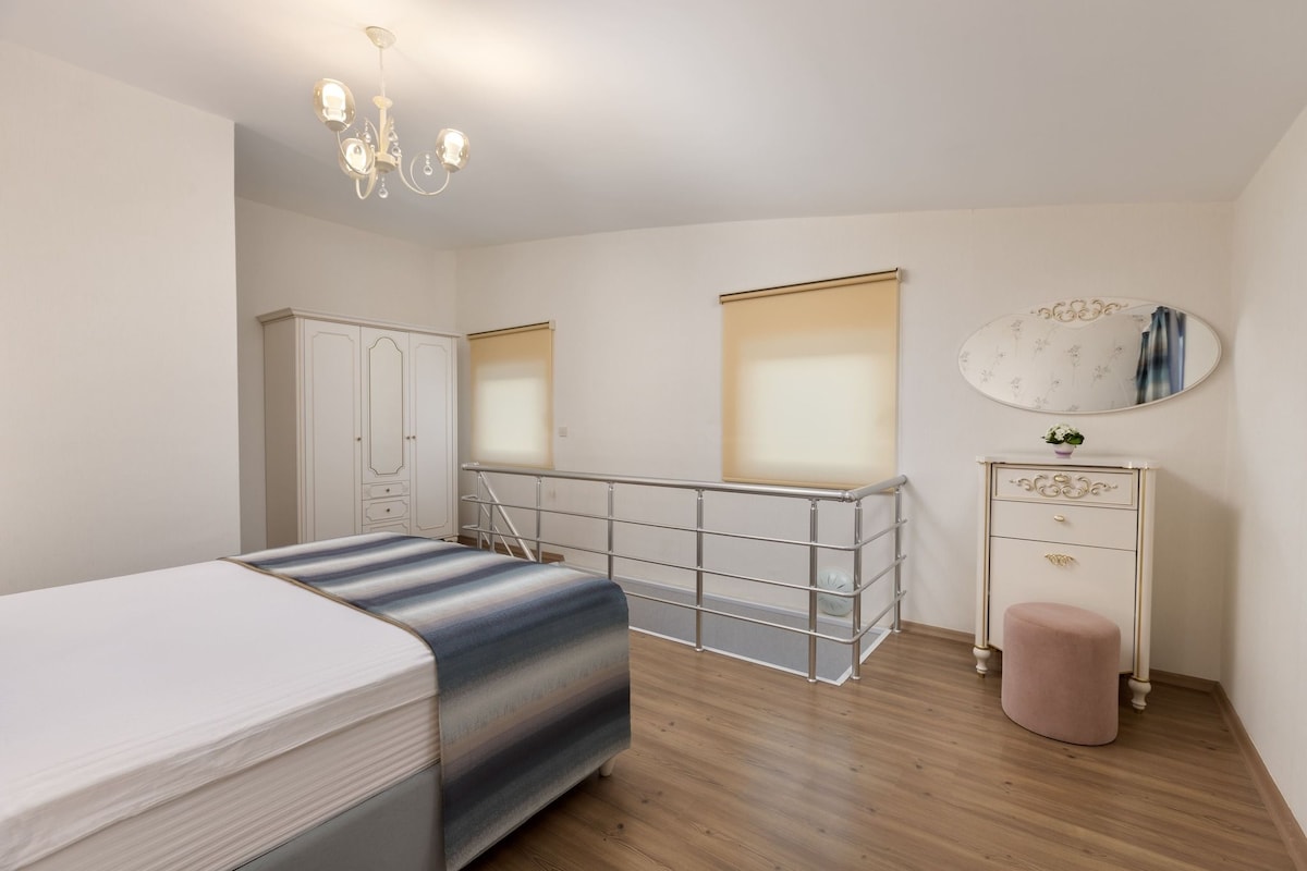 Une chambre à coucher avec un lit, une commode, un miroir et un lustre.