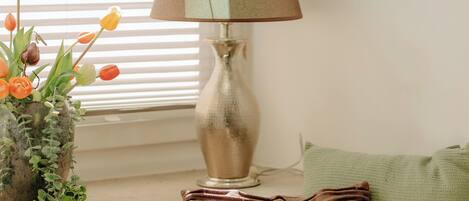 A window seat with a lamp, a cushion, and a plant with flowers.