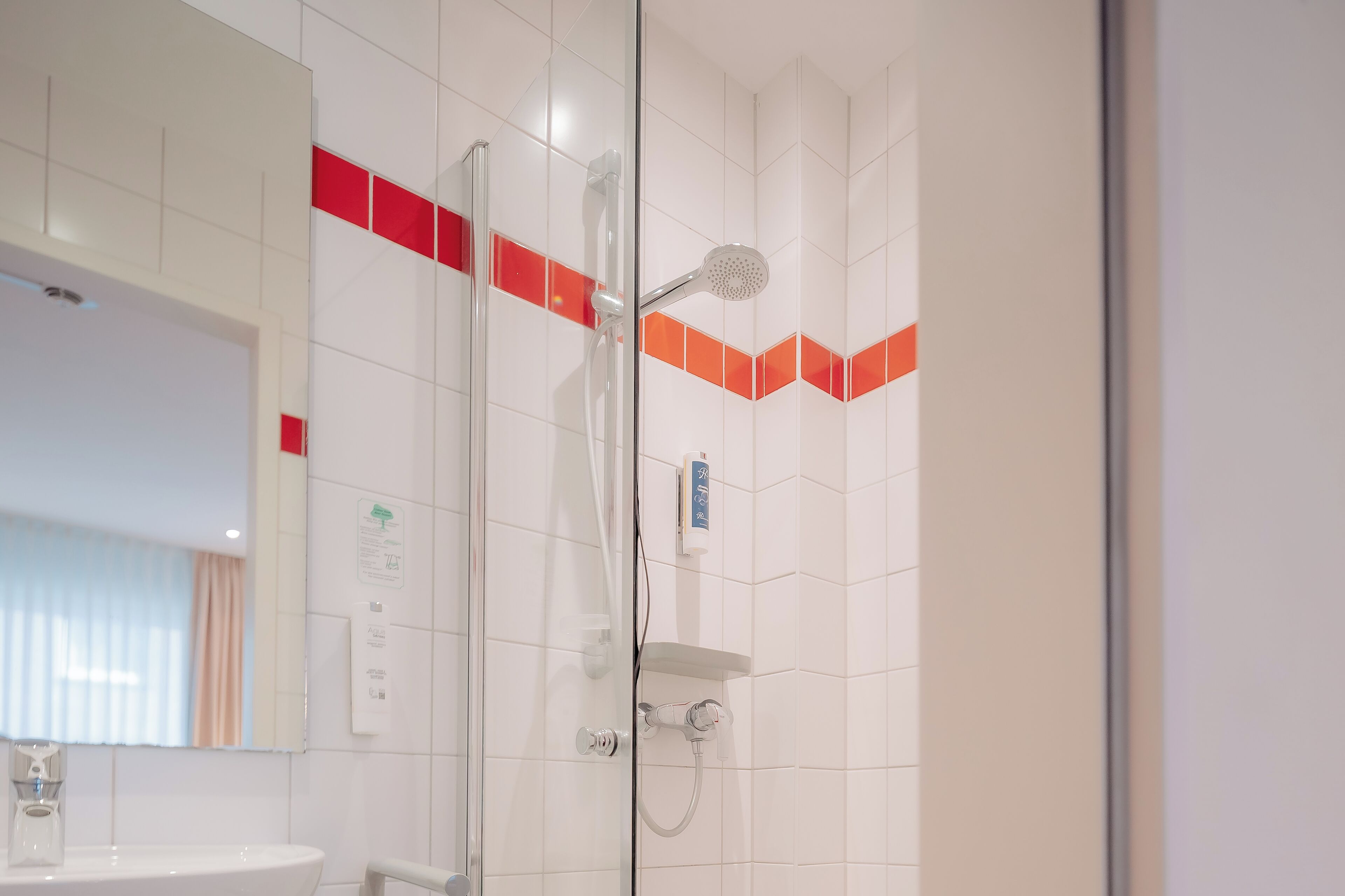 A bathroom with a glass shower enclosure, a white sink, and a mirror.