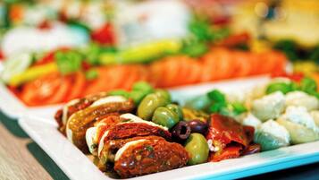 Una variedad de platos coloridos en un plato blanco, con aceitunas, tomates y posiblemente mariscos.