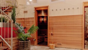 A wooden sauna room with a bench, a wooden door, and a stone floor. - INSIDE Nordhorn by Hackmann (Nordhorn)