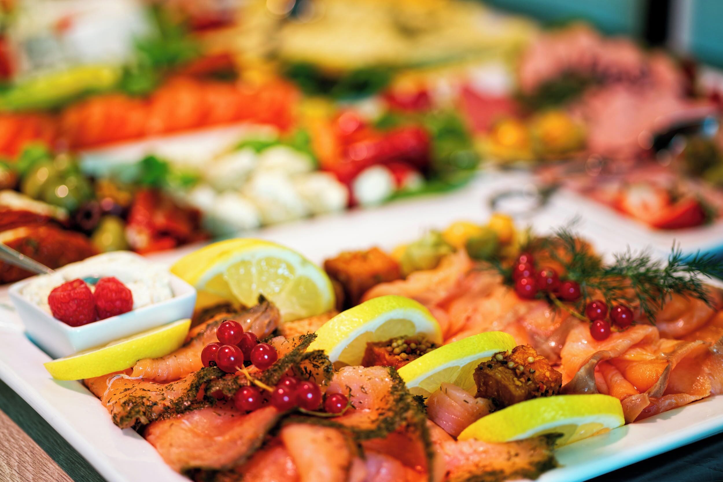 Una bandeja con diversos alimentos, como salmón, rodajas de limón, bayas y hierbas.