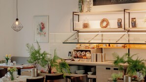 A restaurant interior with a dining area, a counter with food items, and a hanging light fixture. - INSIDE Nordhorn by Hackmann (Nordhorn)