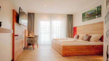 Una habitación de hotel con una cama de madera, un escritorio y un televisor.