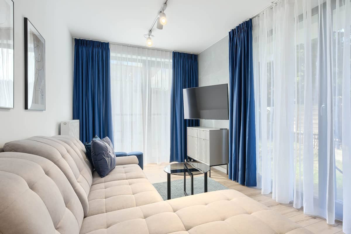 Ein modernes Wohnzimmer mit einem beigefarbenen Sofa, einem Glastisch und einem an der Wand montierten Flachbildfernseher.
