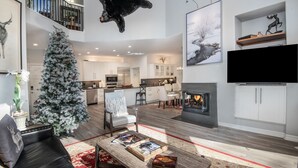 En rummelig opholdsstue med pejs, juletræ og et moderne køkken i baggrunden.
