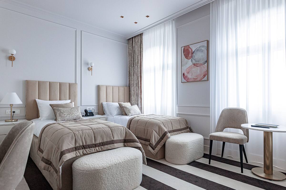 Une chambre d’hôtel moderne avec deux lits, un coin salon et une petite table.
