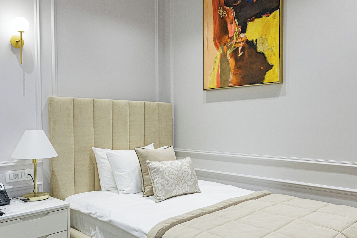 Une chambre à coucher moderne avec un grand lit, une table de chevet avec une lampe et un tableau au mur.