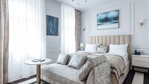 Una habitación de hotel moderna con una cama grande, una mesa redonda y vistas a la ciudad a través de cortinas translúcidas.