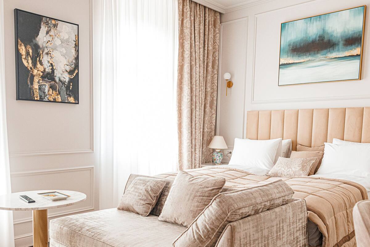 Une chambre à coucher moderne avec un grand lit, une table de chevet, une lampe et deux tableaux accrochés aux murs.
