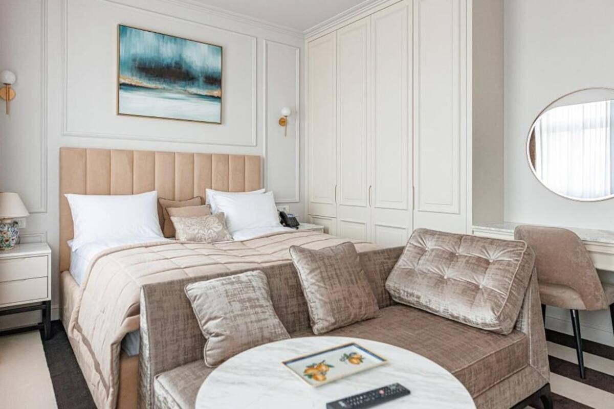 Une chambre d’hôtel avec un grand lit, un canapé, une table basse ronde et un tableau au mur.
