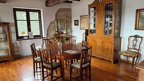 A dining room with a wooden table, chairs, a cabinet with glass doors, and a window with a view.