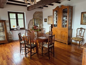 A dining room with a wooden table, chairs, a cabinet with glass doors, and a window with a view.