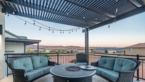 Un espace extérieur aménagé, abrité et doté de deux canapés et d’une table ronde, offrant une vue sur un paysage pittoresque.