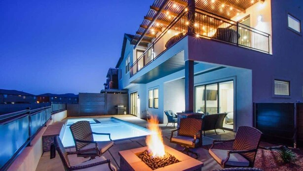 A modern two-story building with a rooftop pool, outdoor seating, and a fire pit.