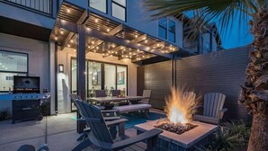 An outdoor patio with a fire pit, seating area, and a grill.