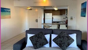 Un espacio habitable compacto con un conjunto de sofás, kitchenette y comedor.
