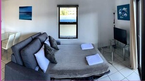 Una habitación moderna con cama, sofá, televisión y ventana con vistas.