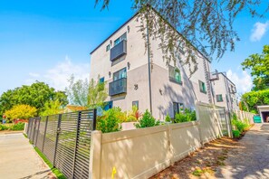 Un immeuble moderne à plusieurs étages, doté de balcons, d’une entrée sécurisée et d’un jardin bien entretenu.