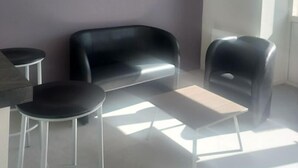Ein modernes Zimmer mit einem schwarzen Ledersofa, einem kleinen runden Tisch und einer Bar.