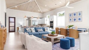 A spacious living area with a blue sofa, white armchairs, and a coffee table.
