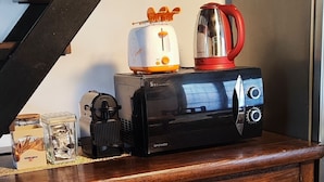 Un meuble en bois sur lequel sont posés un grille-pain, une bouilloire et une machine à café.