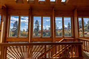 A wooden cabin with large windows offering views of trees and a clear sky. - Beautiful Home, Great Forest View, Game Room (Pagosa Springs)