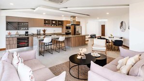 Eine moderne Küche mit einer zentralen Kochinsel, Barhocker und einem Essbereich mit Tisch und Stühlen.