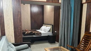 A modern bedroom with a bed, a sofa, a glass-top coffee table, and a wooden chair.