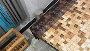 A room with a checkered floor, a bed with a patterned bedspread, a wooden chair, and a small table.