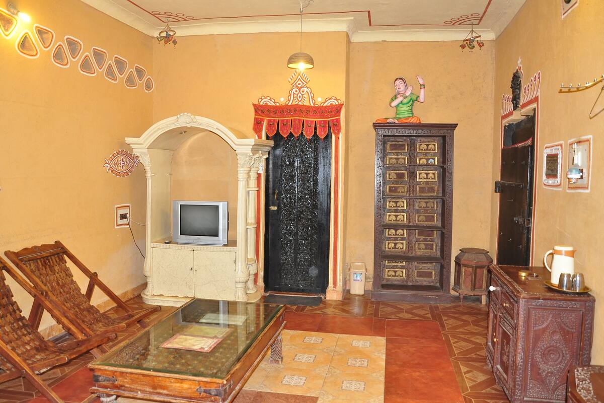 A traditional living room with a television, wooden furniture, and a decorative cabinet.