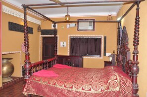 A traditional room with a four-poster bed, a large brass pot, and a window with curtains. - NAKHRALI DHANI VILLAGE RESOTR LLP (Indore)