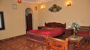 A room with a large bed, wooden furniture, and a decorative wall piece. - NAKHRALI DHANI VILLAGE RESOTR LLP (Indore)
