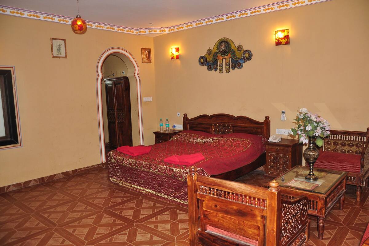 A room with a large bed, wooden furniture, and a decorative wall piece.