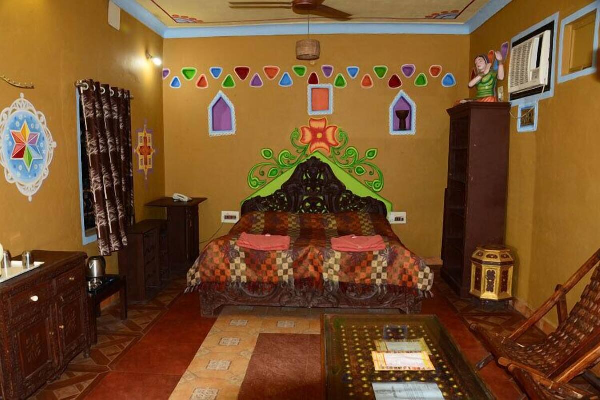 A room with a bed, a wooden cabinet, a small table, and a chair.