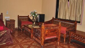A traditional room with a wooden sofa set, a television, and a decorative vase. - NAKHRALI DHANI VILLAGE RESOTR LLP (Indore)