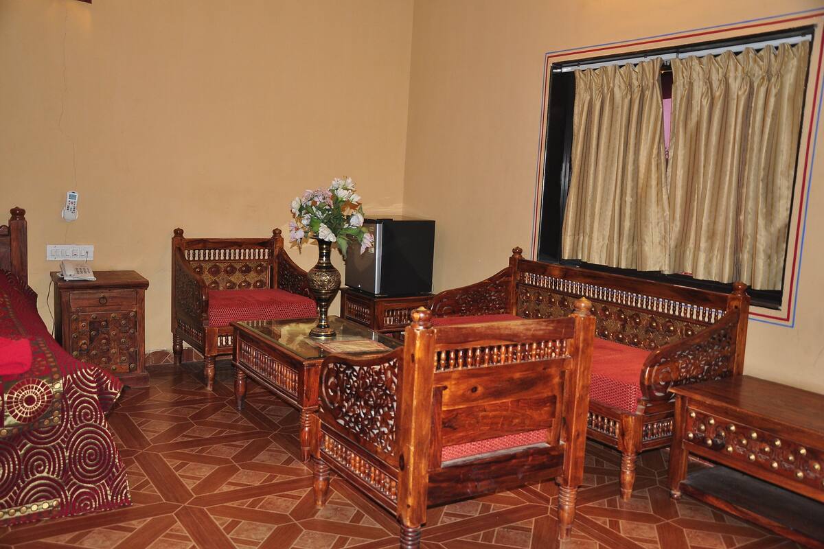 A traditional room with a wooden sofa set, a television, and a decorative vase.