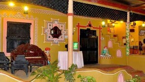 A room with a piano, a television, and a decorative wall with geometric patterns. - NAKHRALI DHANI VILLAGE RESOTR LLP (Indore)