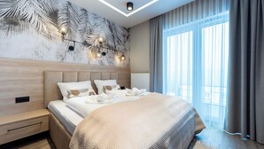 A modern hotel room with a large bed, a wall mural, and a large window with curtains. - Apartamenty Sun & Snow Hillside (Karpacz)