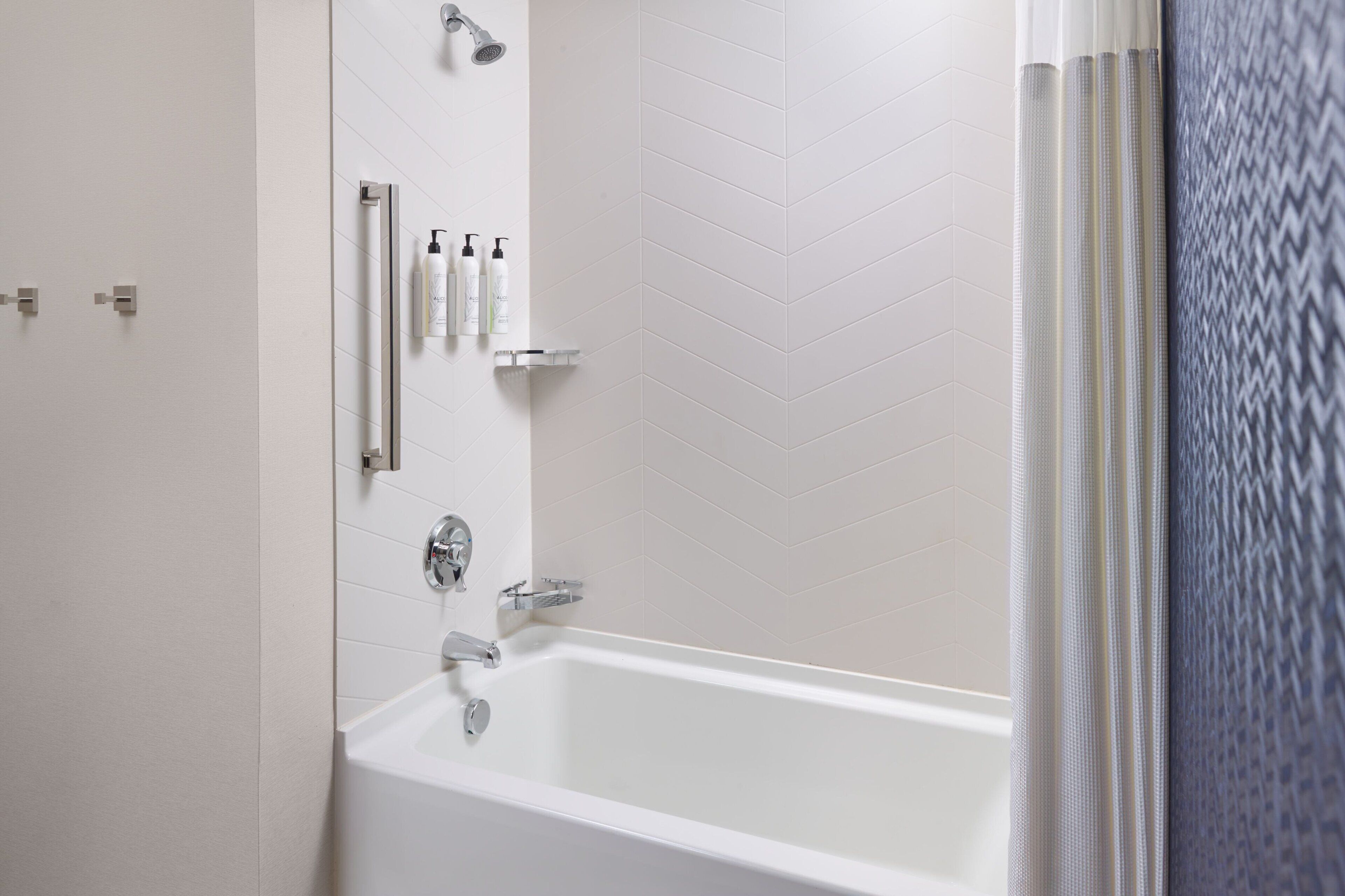 A modern bathroom with a white bathtub, chrome fixtures, and a showerhead.